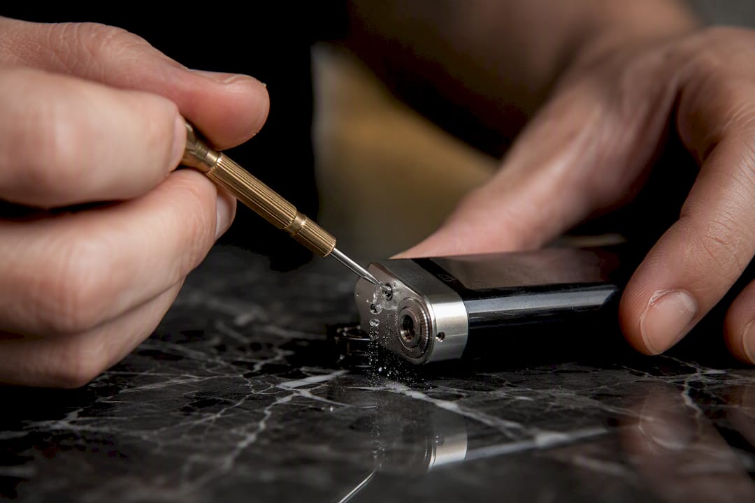Hands bleeding butane lighter valve with screwdriver