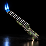 A metallic double-barrel torch lighter with a green and brown camouflage patterned body, shown lit with two bright blue flames — view 2